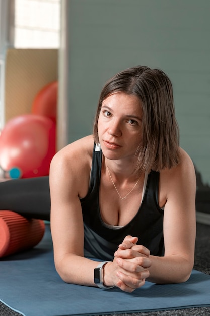 Jeune femme sexy en tenue de sport tout en s'entraînant sur un tapis de yoga. Portrait d'instructeur de conditionnement physique.