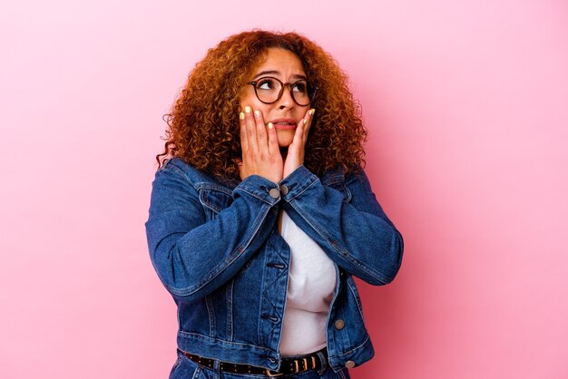 Jeune femme sinueuse latine isolée sur un mur rose effrayé et effrayé.