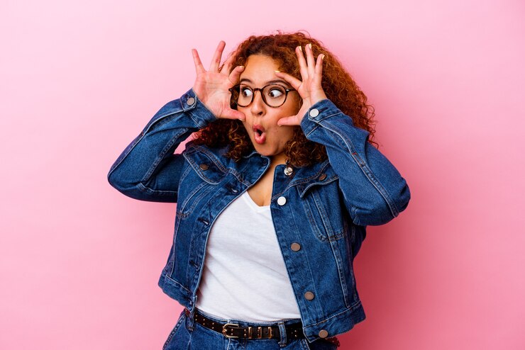 Photo jeune femme sinueuse latine isolée sur un mur rose en gardant les yeux ouverts pour trouver une opportunité de succès.