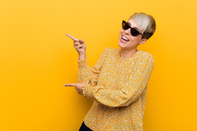 Jeune femme sinueuse portant un vêtement d'été floral excité pointant avec l'index loin.