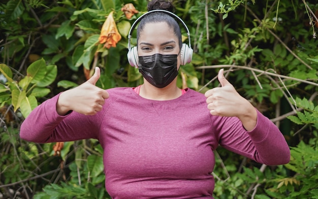 Photo jeune femme sinueuse avec les pouces vers le haut portant un masque de sécurité et un casque - fille faisant du sport dans le parc de la ville