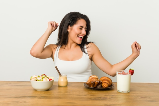 Jeune femme sinueuse prenant un petit déjeuner dansant et s'amusant.