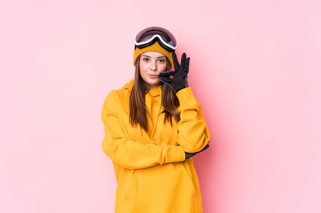 Jeune femme skieur caucasien avec les doigts sur les lèvres gardant un secret.