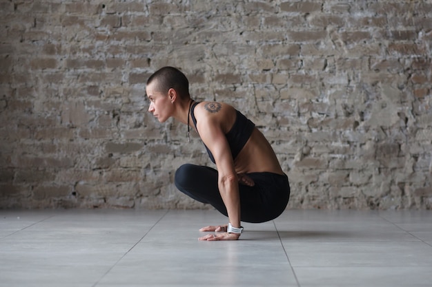 Photo jeune femme skinhead faisant des exercices d'équilibre de yoga - tolasana indoor