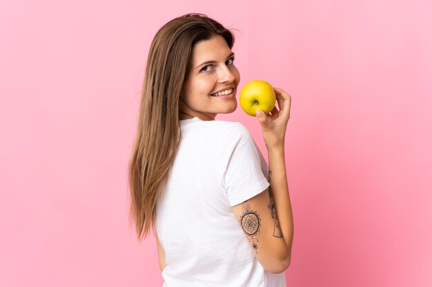 Jeune femme slovaque isolée sur rose manger une pomme