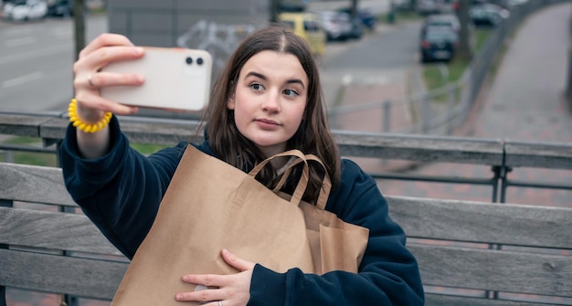 Une jeune femme avec un smartphone et un colis dans les mains