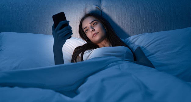 Jeune femme, à, smartphone, coucher lit