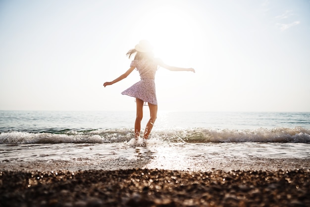 Jeune femme solitaire marche sur le bord de mer au coucher du soleil