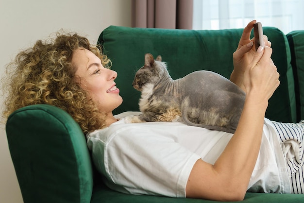 Jeune femme et son chat mignon allongé sur le canapé à la maison