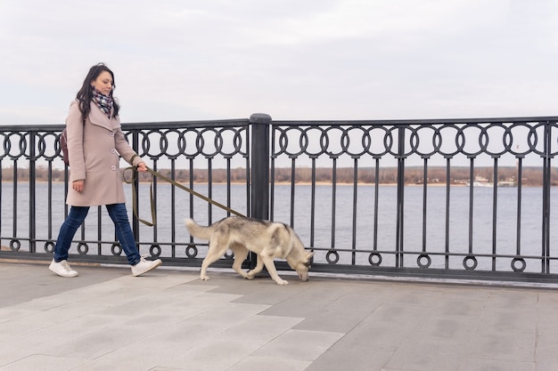 Jeune femme avec son chien husky marchant le long du remblai un jour d'automne