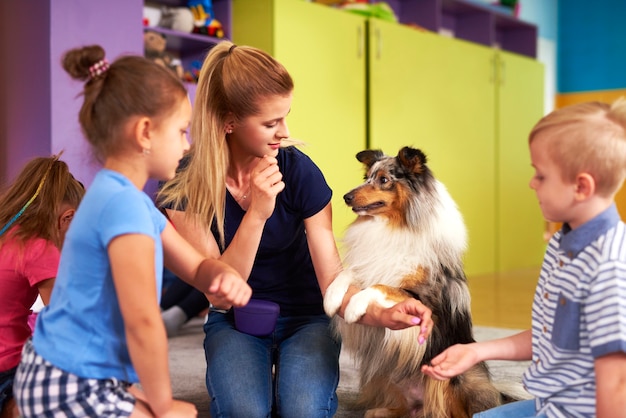 Jeune femme et son chien jouant avec des enfants pendant la thérapie