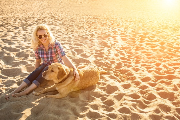 Jeune femme avec son chien à la plage sun flare