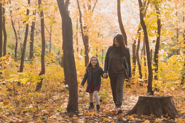 Jeune femme et son enfant fille marchant dans le parc d'automne concept de parent seul et de maternité