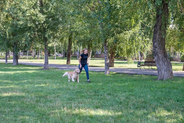 Jeune femme avec son retriever dans un parc d'été.