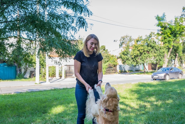 Jeune femme avec son retriever dans le parc.