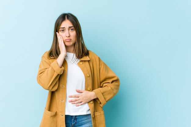 Jeune femme souffle sur les joues, a une expression fatiguée