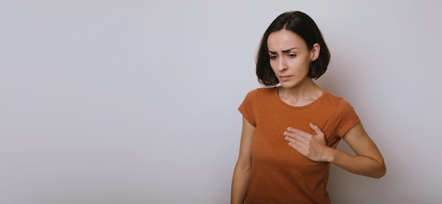 Jeune femme souffrant d'une crise cardiaque isolée sur fond gris