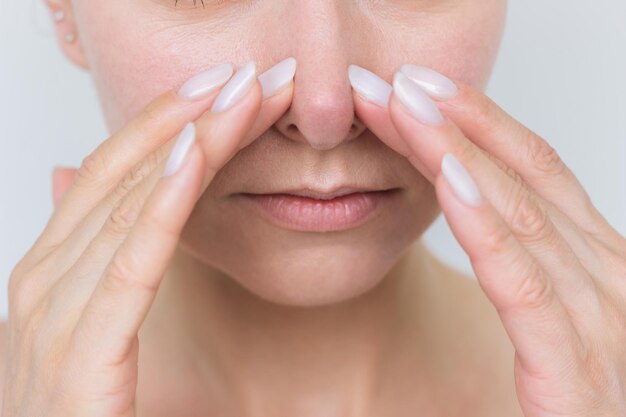 une jeune femme souffre d'une congestion nasale et d'un nez qui coule tient le nez avec les deux mains
