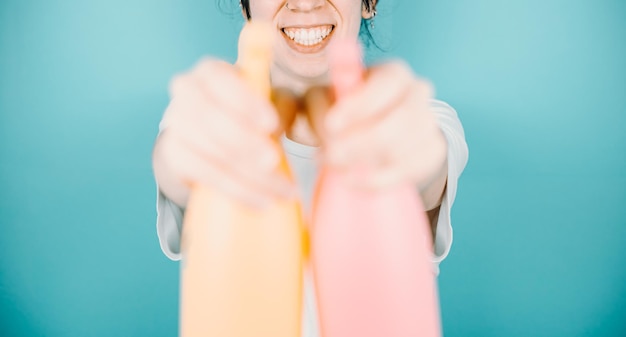 Jeune femme souriant joyeusement à la caméra tout en visant à la caméra une paire de pulvérisateurs d'eau pour se rafraîchir pendant les vacances d'été à l'extérieur avec espace de copieImage d'arrière-plan couleur