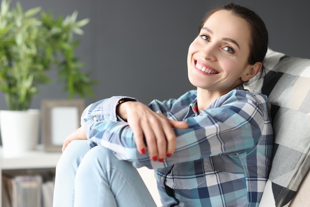 Jeune femme souriante assise sur un canapé à la maison