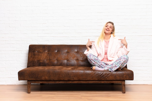 Jeune femme souriante et assise sur le canapé