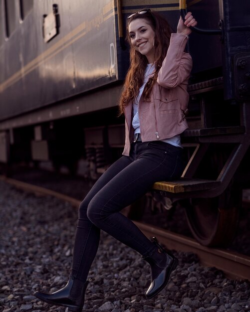 Photo une jeune femme souriante assise sur les marches du train