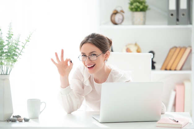 Une jeune femme souriante au bureau est très heureuse d'une commande réussie