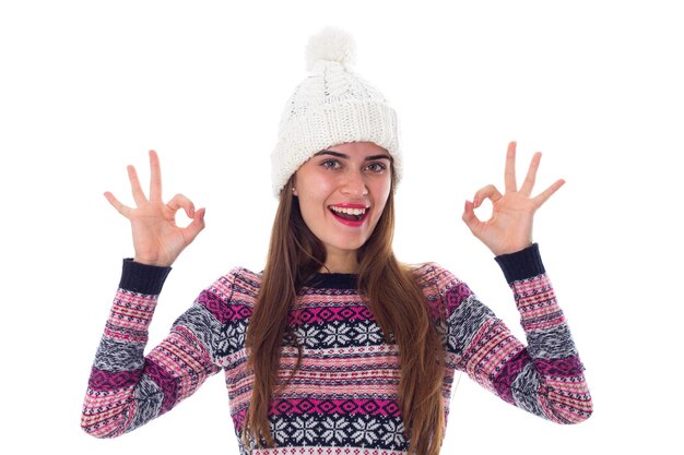 Jeune femme souriante au chapeau blanc et pull violet montrant bien sur fond blanc en studio