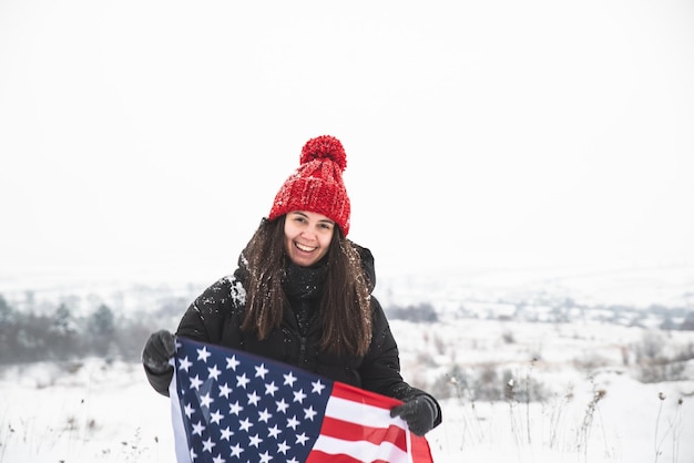 Jeune femme souriante au chapeau rouge tenant le drapeau usa heure d'hiver