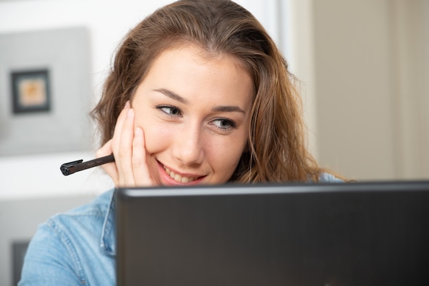 Jeune femme souriante aux cheveux longs utilise un ordinateur portable