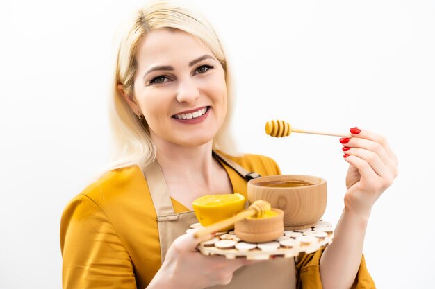 jeune femme souriante avec bol de miel sur fond blanc