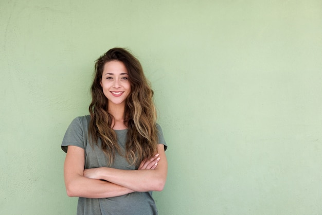 Jeune femme souriante avec les bras croisés sur fond vert