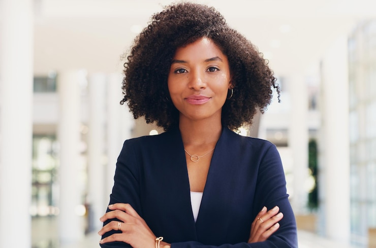 Photo une jeune femme souriante avec les bras croisés se tient au bureau.