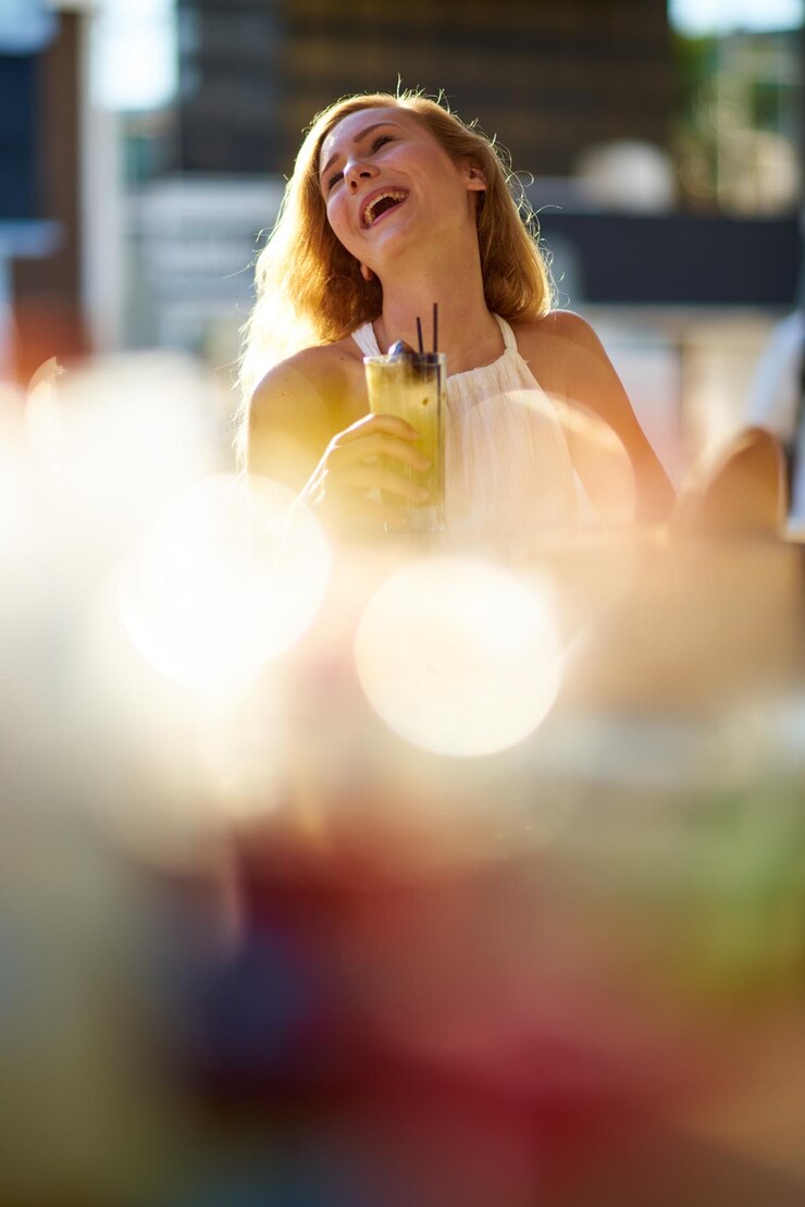 Photo une jeune femme souriante buvant un verre par une journée ensoleillée.