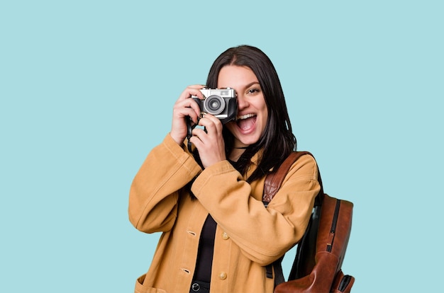 Jeune femme souriante avec caméra argentique regardant à travers le viseur excitée par une nouvelle passion