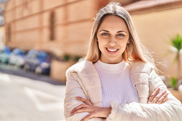 Jeune femme souriante confiante debout avec les bras croisés geste dans la rue