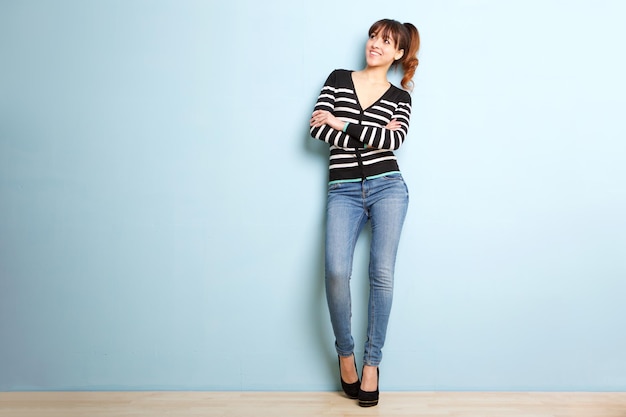 Une jeune femme souriante contre le mur bleu.