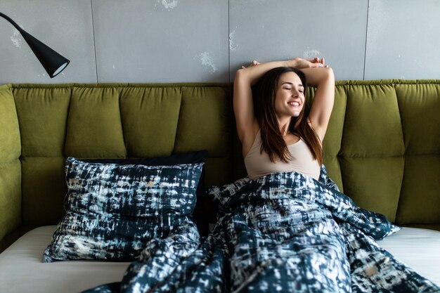 Jeune femme souriante, couché dans son lit dans la chambre