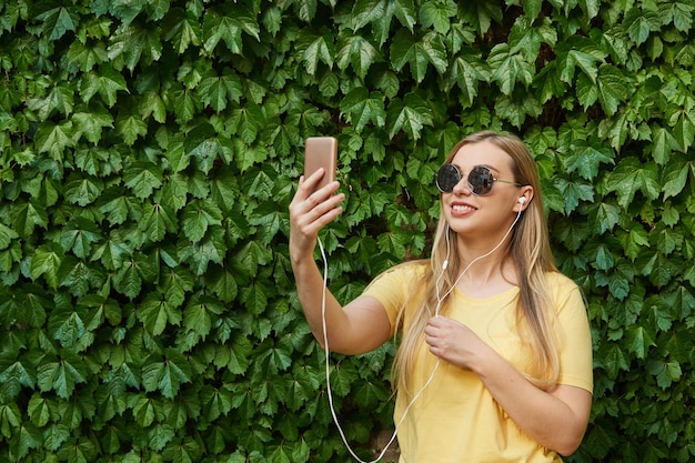 Une jeune femme souriante dans un t-shirt jaune parle lors d'un appel vidéo à l'aide d'un téléphone portable