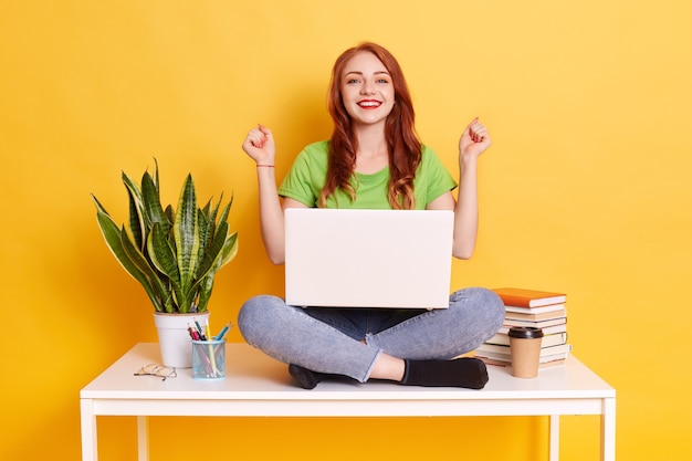 Jeune femme souriante dans des vêtements décontractés, serrant les poings comme gagnant