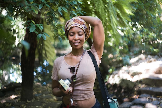 Une jeune femme souriante debout contre des arbres dans la forêt