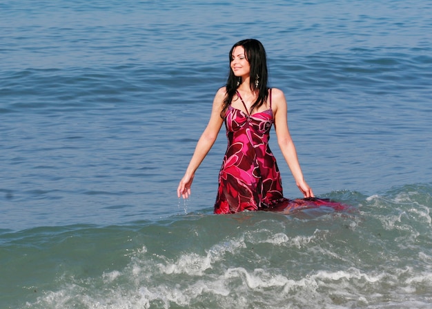 Jeune femme souriante debout dans les vagues de la mer