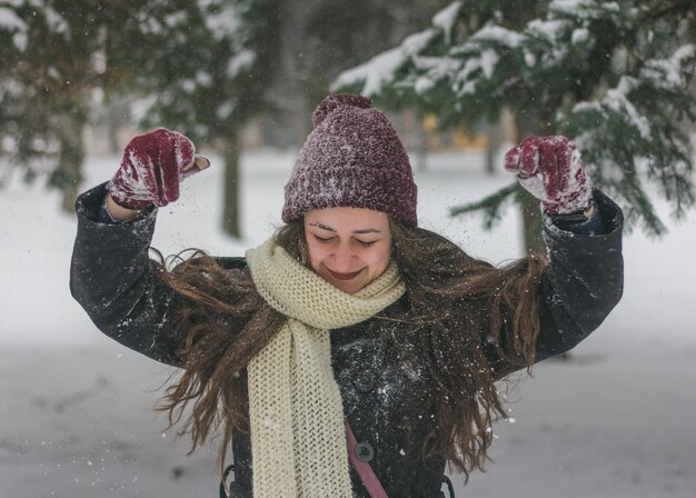 Photo une jeune femme souriante debout à l'extérieur pendant la chute de neige