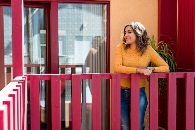 Photo une jeune femme souriante debout près de la balustrade du balcon.