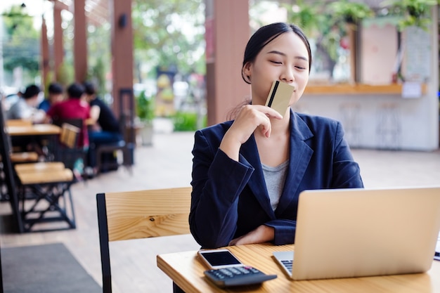 Jeune femme souriante. Femme d&#39;affaires détient une carte de crédit et d&#39;utiliser un ordinateur portable. Concept de magasinage en ligne