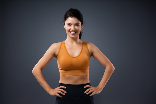 Jeune femme souriante en forme attrayante en haut debout avec les mains sur les hanches.