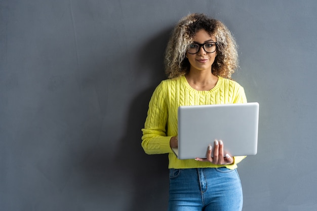 Photo jeune femme souriante heureuse dans des vêtements décontractés tenant un ordinateur portable et envoyant un courrier électronique à sa meilleure amie.