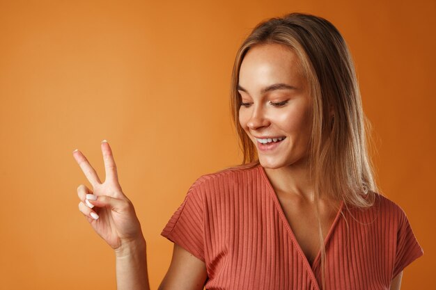 Jeune femme souriante heureuse montrant le signe de la victoire, portrait.