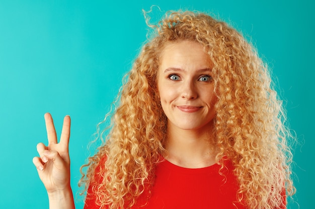 Jeune femme souriante heureuse montrant le signe de la victoire