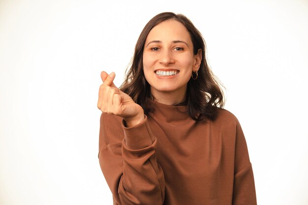 Une jeune femme souriante et heureuse montre le symbole du cœur coréen avec deux doigts